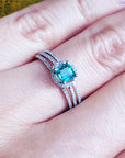 A natural emerald engagement ring in white gold on a person's finger.