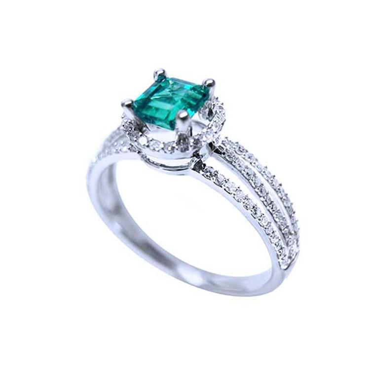 Emerald engagement ring with halo diamonds and three rows of diamonds on a 14K white gold band.