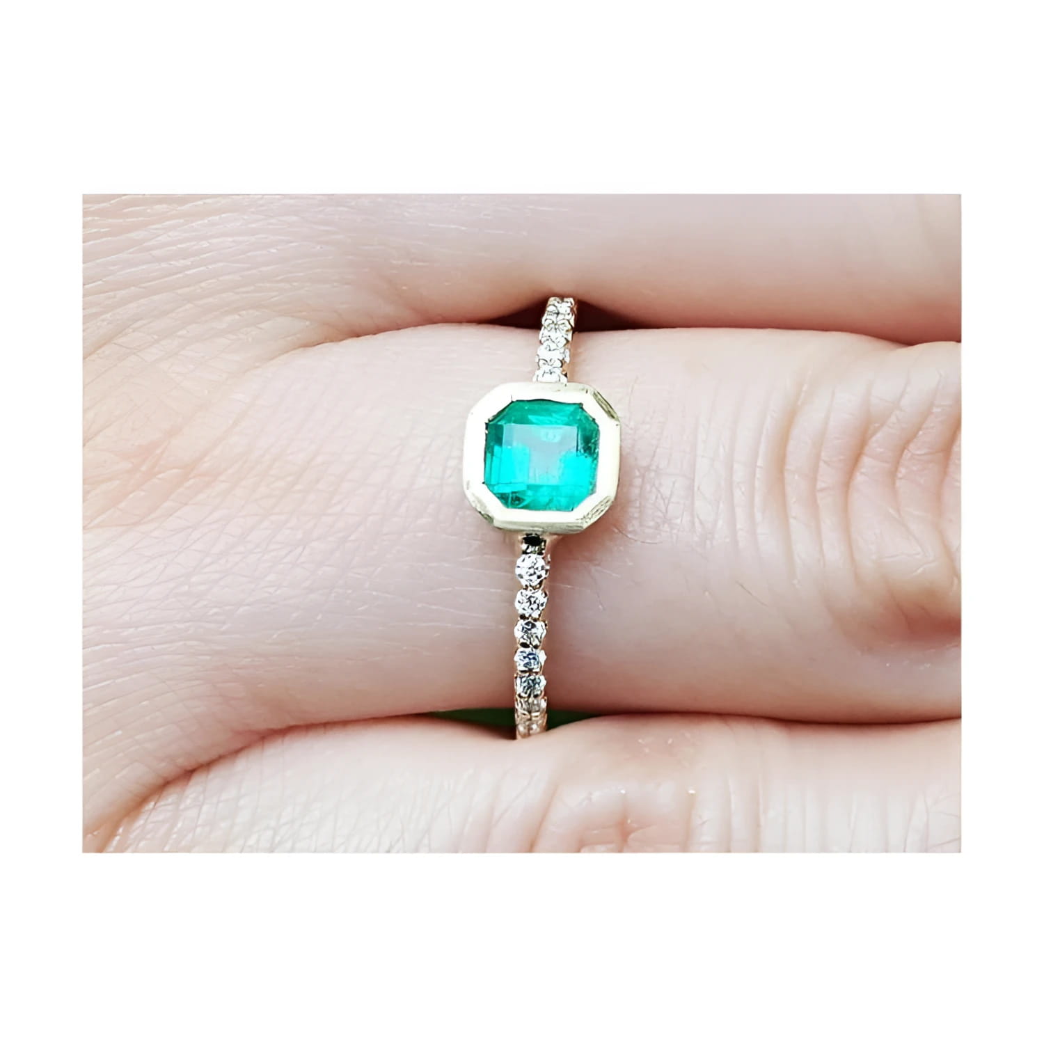 14K yellow gold ring with a 0.61 ct. medium green emerald in a tapered bezel, flanked by natural diamonds.