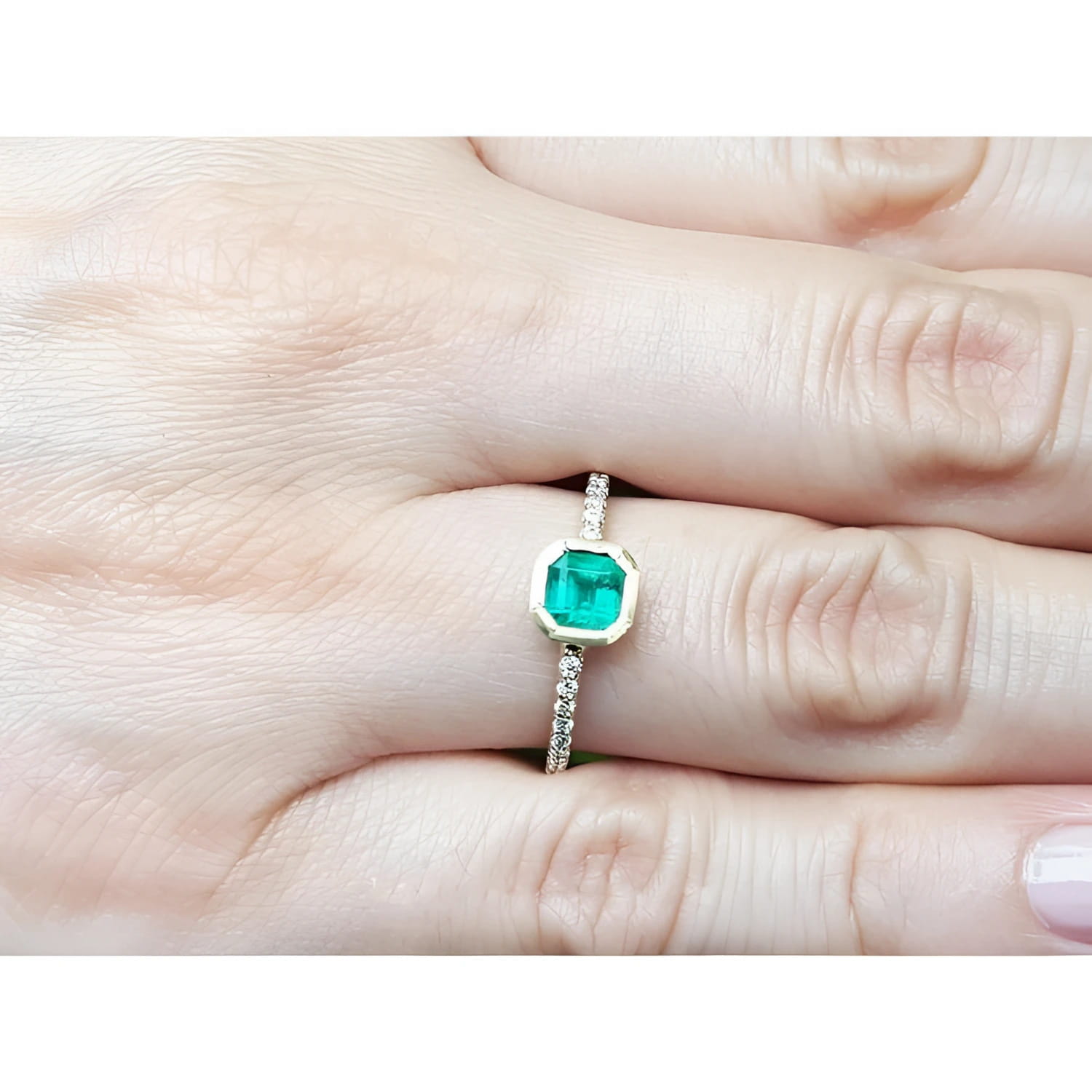 14K yellow gold ring with a medium green emerald in a tapered bezel, flanked by natural diamonds.