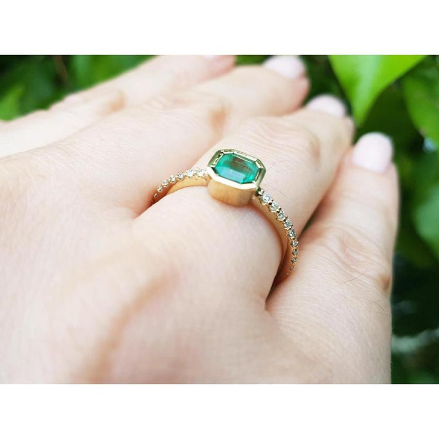 14K yellow gold ring with a 0.61 ct emerald in a tapered bezel and diamond-studded band.
