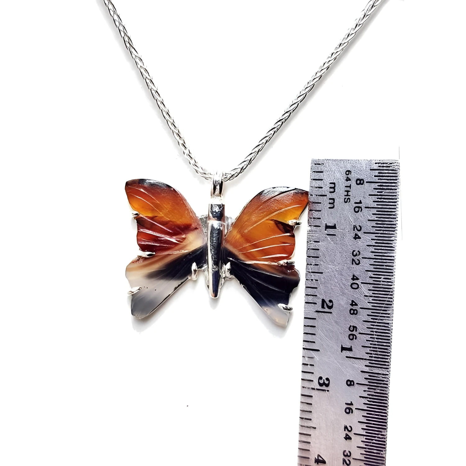 Sterling silver agate butterfly pendant necklace with orange, brown, and black wings, shown with a ruler.