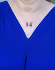 Person wearing a blue dress with an agate butterfly-shaped necklace