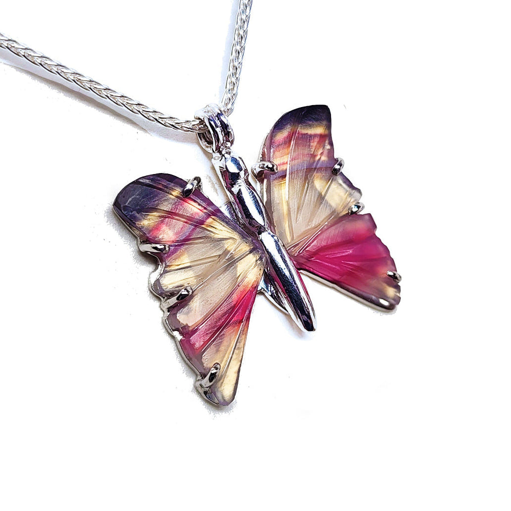 Agate butterfly-shaped silver pendant with pink and purple wings on a white background