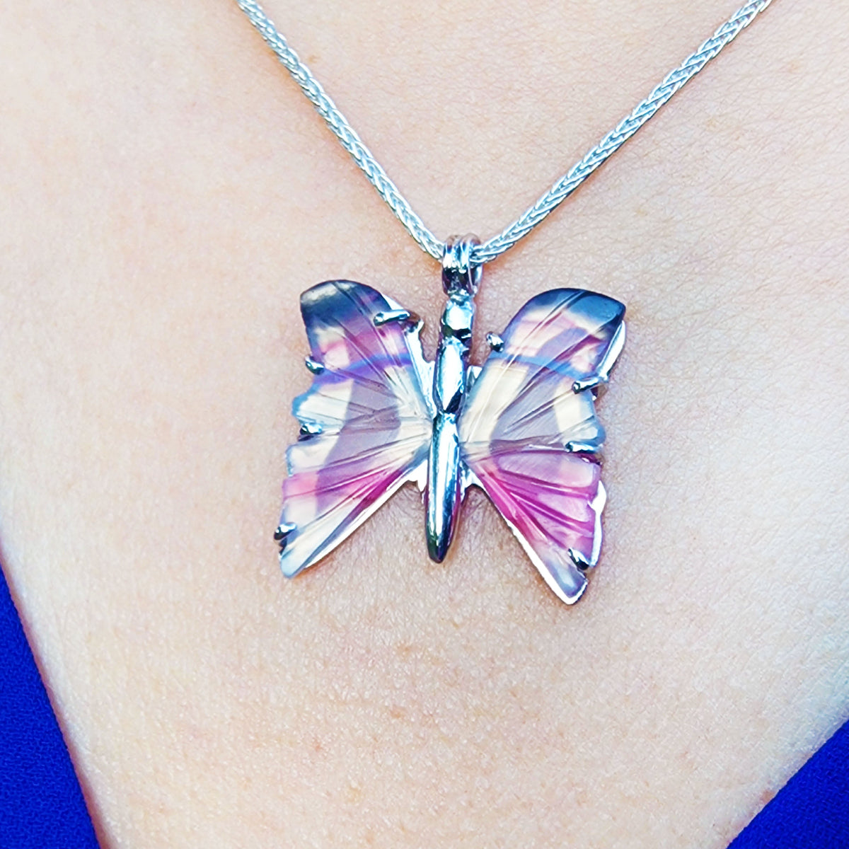 Butterfly-shaped agate silver pendant necklace on a chain against a skin background