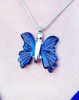 Blue agate butterfly pendant necklace on a person's neck against a neutral background