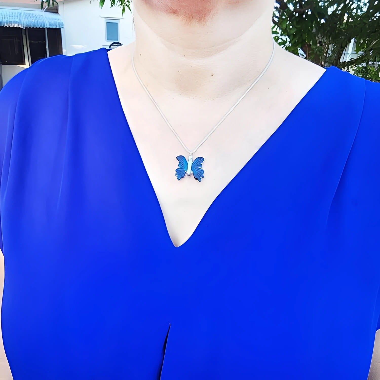 Dark blue natural agate butterfly pendant necklace with silver chain on a woman's neck.