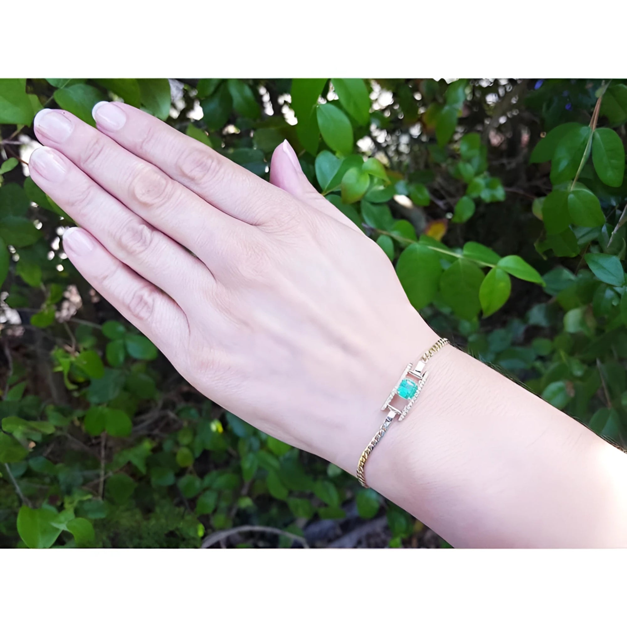 14K yellow gold bracelet with emerald-cut Colombian emerald and diamond accents on a woman's wrist.