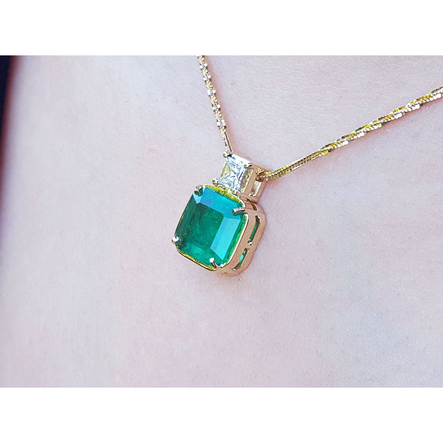 Asscher cut Colombian emerald and princess cut diamond 18K yellow gold necklace on a person.