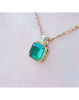Asscher cut Colombian emerald and princess cut diamond 18K yellow gold necklace on a person.
