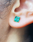 Close-up of an ear wearing an Asscher cut emerald stud earring.