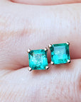  Top close view of an Asscher cut emerald stud earrings on a person's hand.