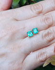  Asscher cut emerald stud earrings on a hand with a natural background.