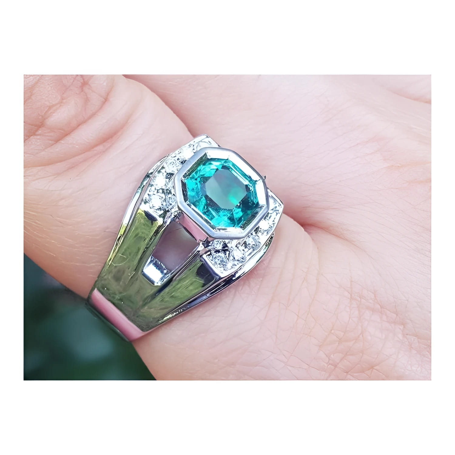 A men's asscher cut natural colombian emerald ring crafted in 18k white gold worn on a finger.