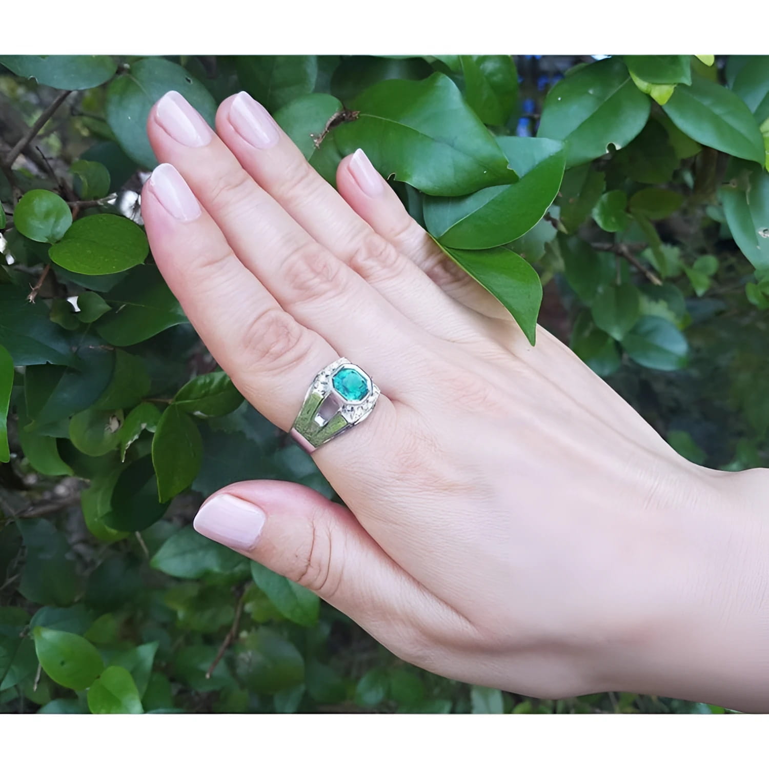 Asscher cut 1.94 ct. bluish-green emerald ring in 18K white gold, worn on a hand.
