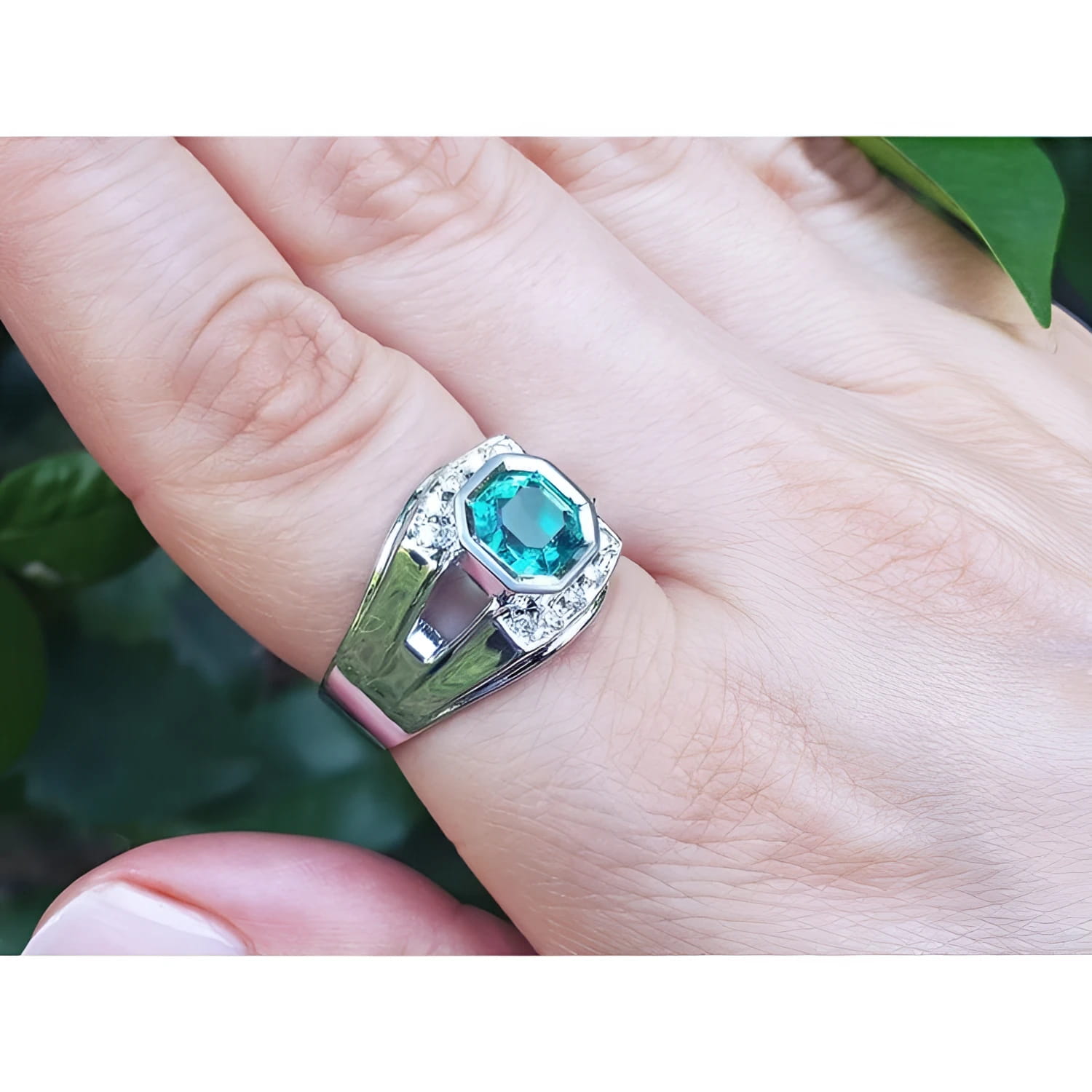 Men's 18K white gold ring with a vibrant bluish-green asscher-cut emerald and side diamonds.