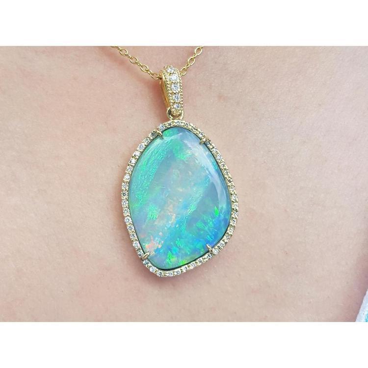 A close-up of an opal pendant necklace on a person's neck with a skin background.