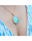 Opal necklace with gold chain on a person wearing a blue and white patterned top.