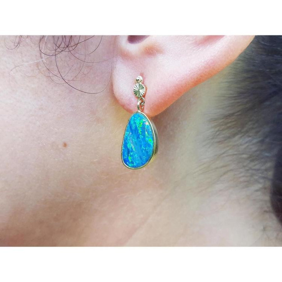 Australian opal doublet dangle earring in 14K yellow gold with bezel setting and push-back closure.