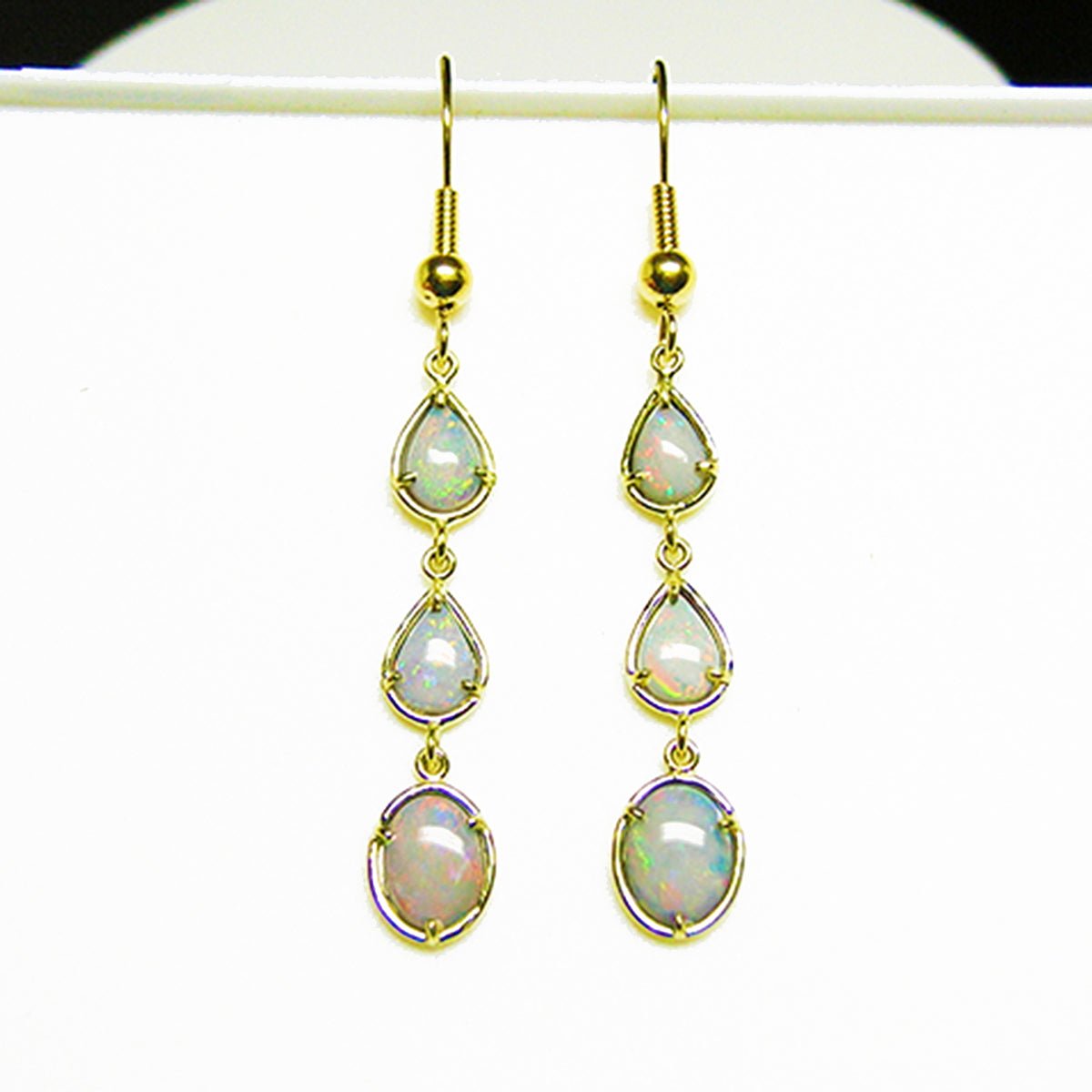 Gold earrings with natural Australian opal stones in yellow gold on a white background.