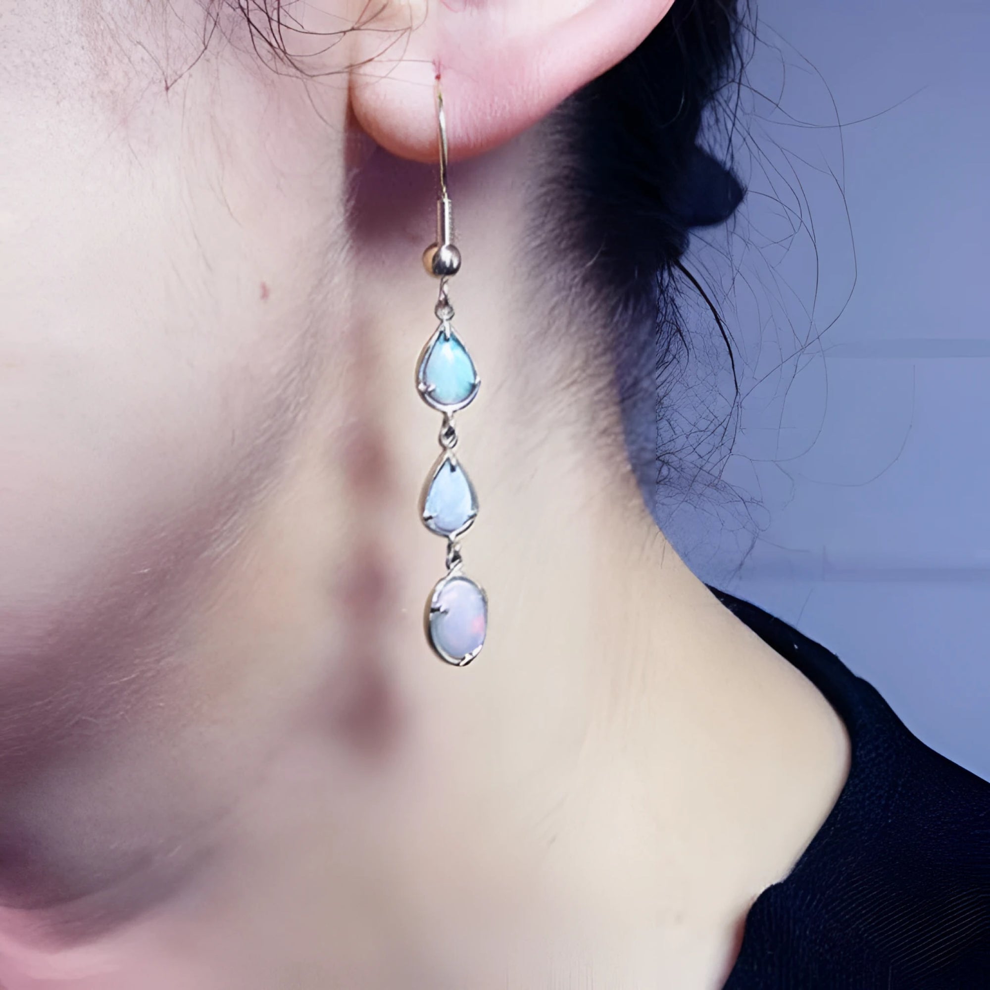 Handcrafted 14k yellow gold earrings with three dangling Australian opals: two pear-shaped, one oval.