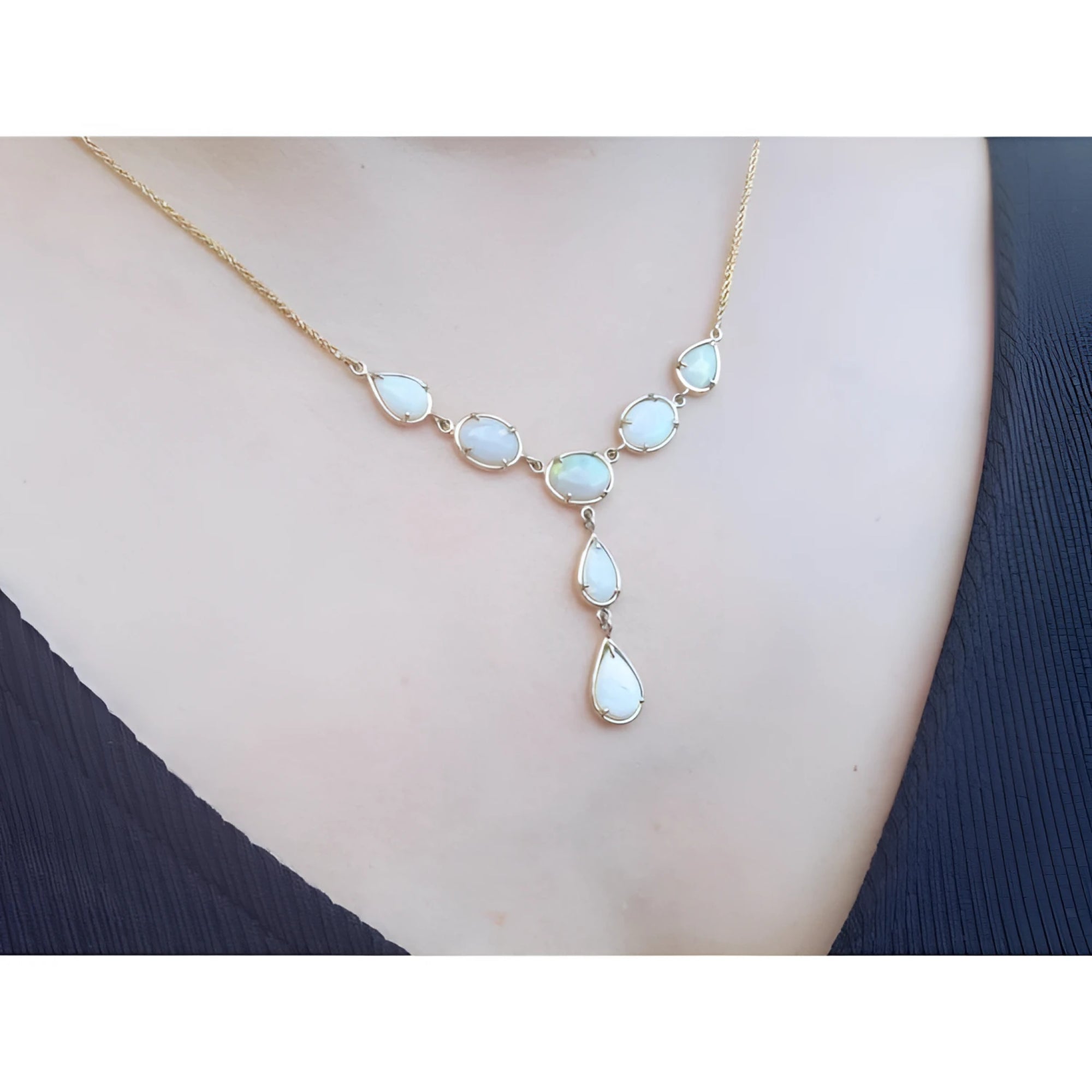 Handcrafted 14K yellow gold necklace with multiple teardrop and oval Australian opals on a woman's neck.