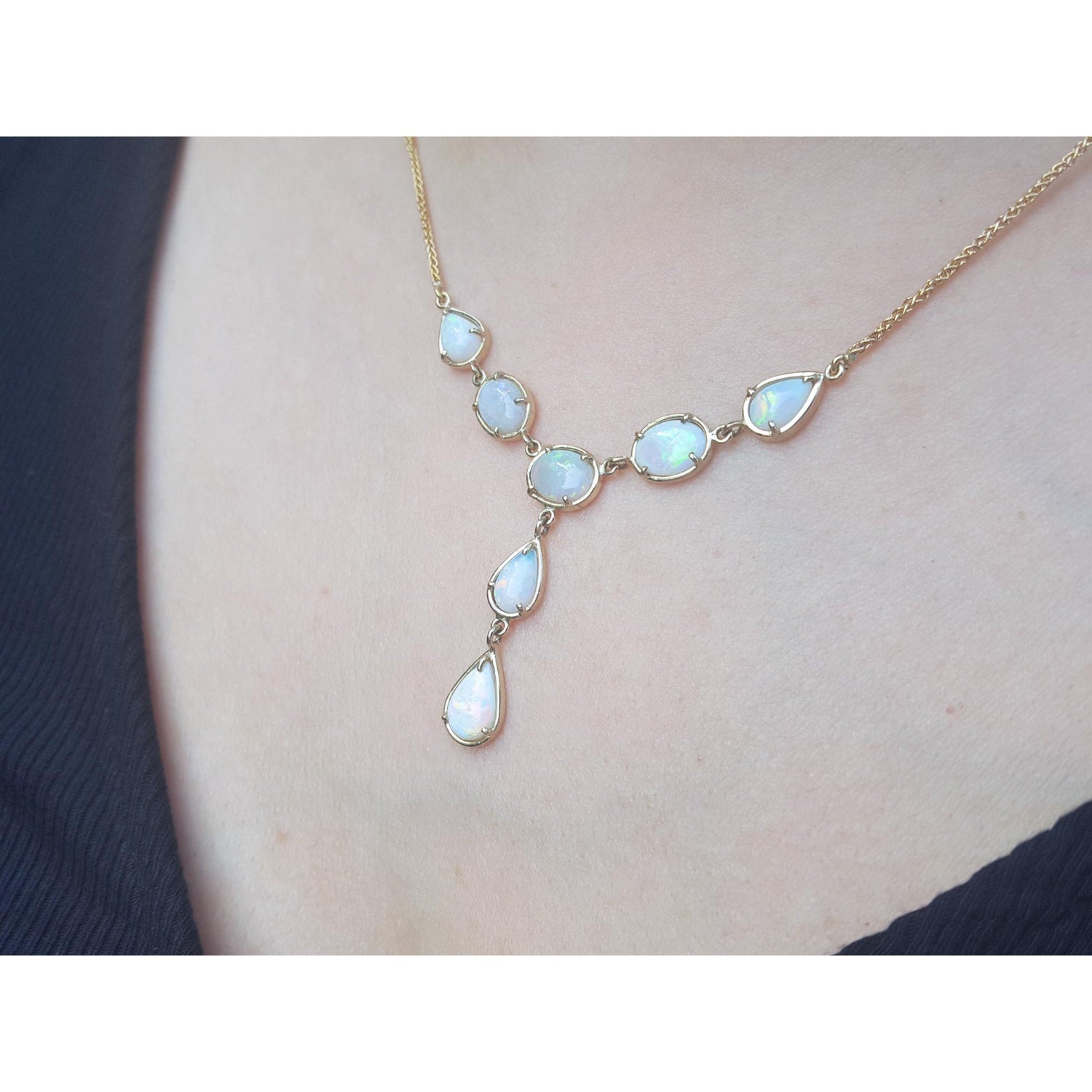 Opal necklace on a person&#39;s neck with a dark background.