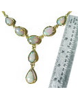 A natural opal necklace with gold setting next to a ruler on a white background.