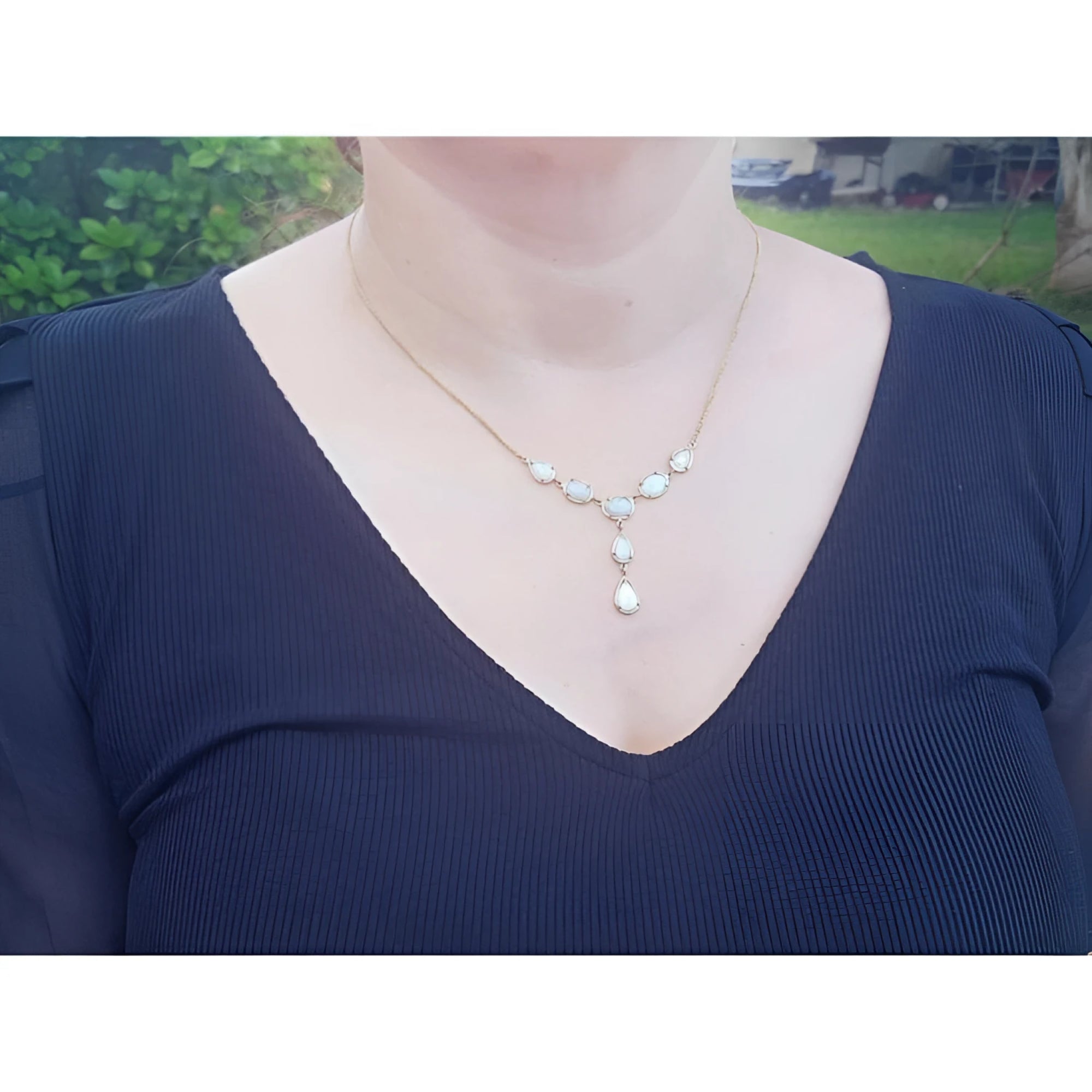 Handcrafted 14K yellow gold necklace with five solid Australian opals, three teardrop, two oval, on a woman's neck.