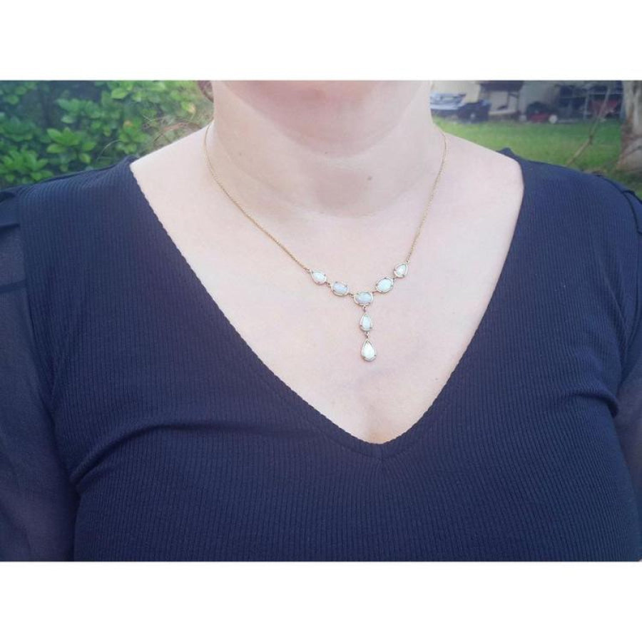 Handcrafted 14K yellow gold necklace with five solid Australian opals, three teardrop, two oval, on a woman's neck.