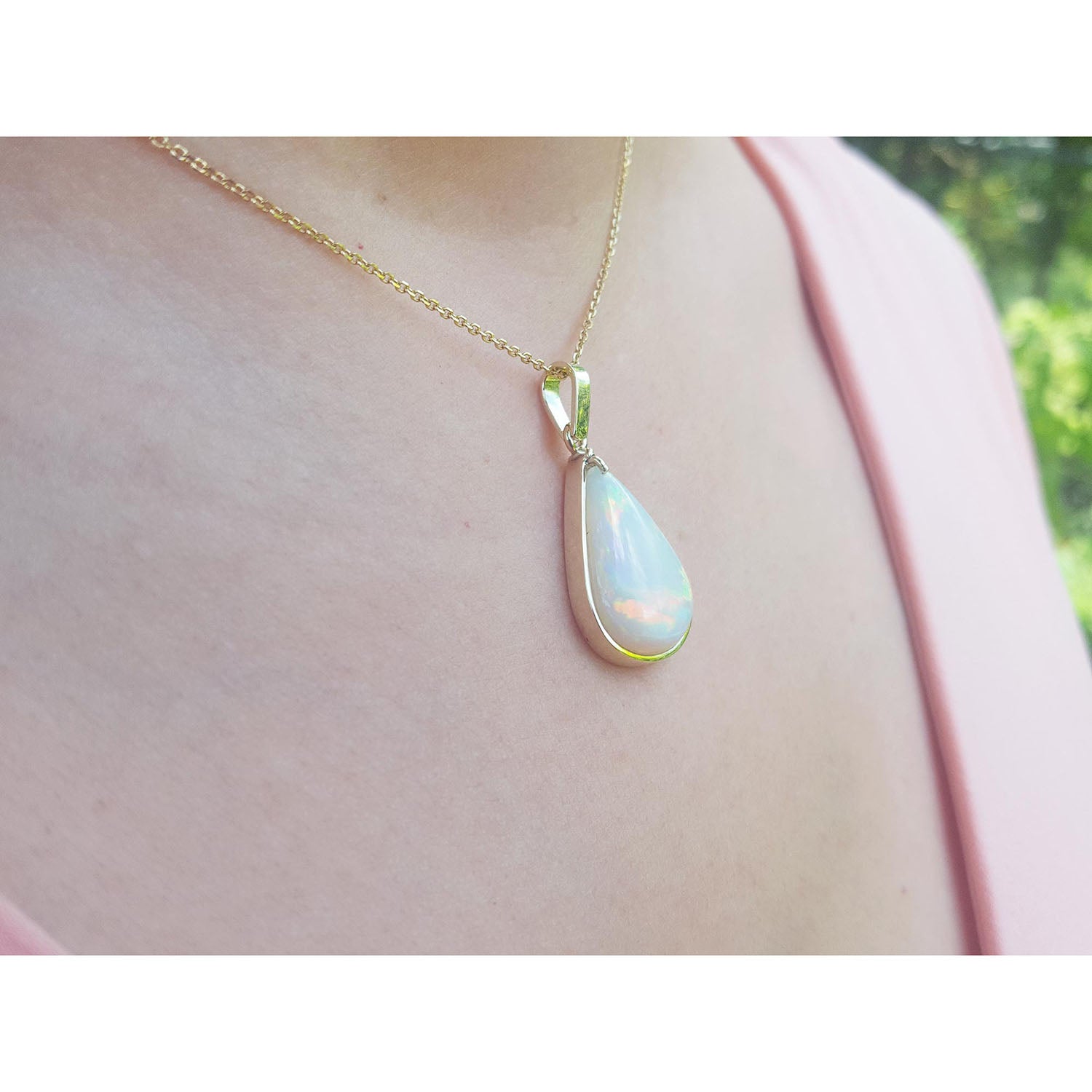 Teardrop-shaped pendant necklace on a person&#39;s neck against a blurred background.