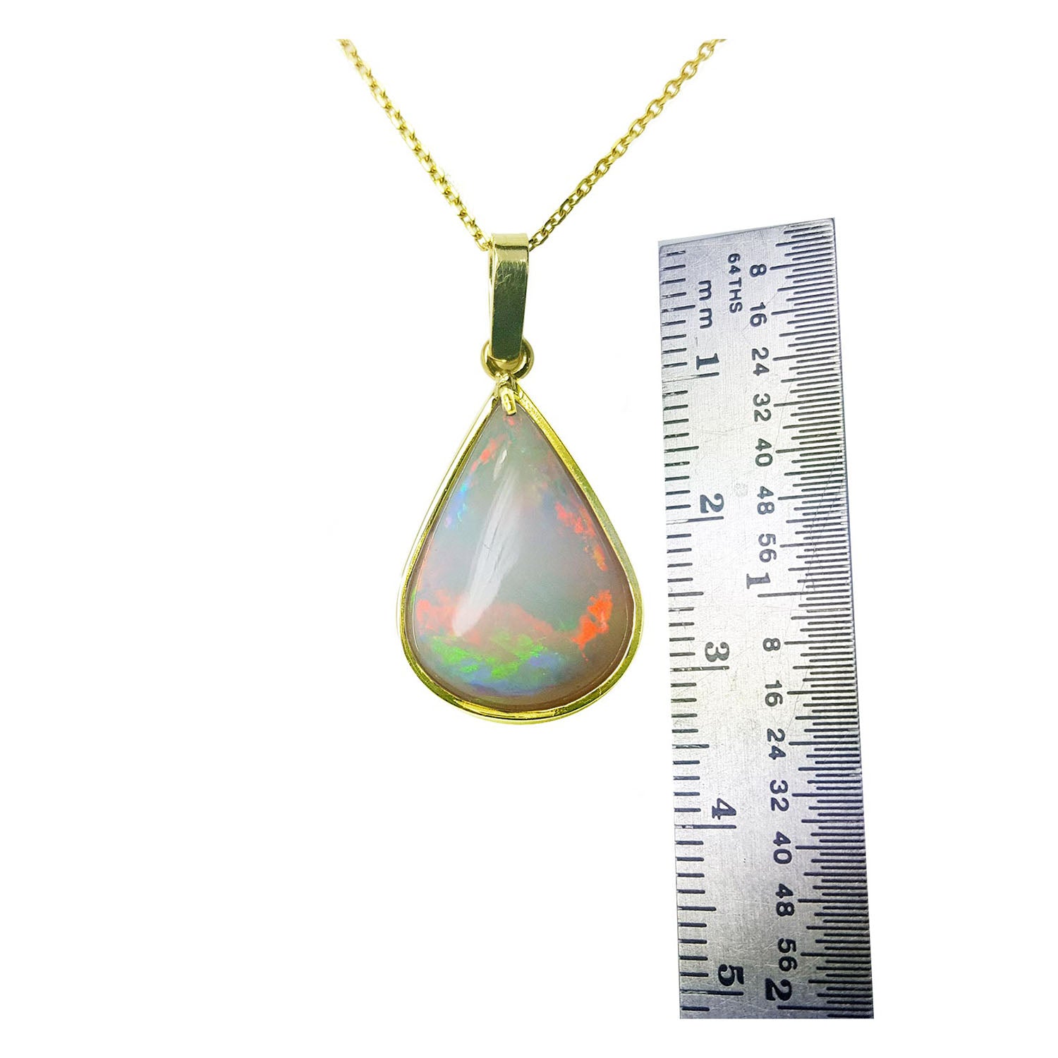 Opal pendant on a gold chain with a ruler for scale on a white background