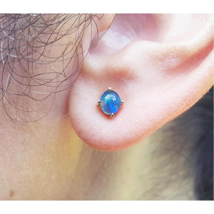 Close-up of an ear with a blue opal earring.