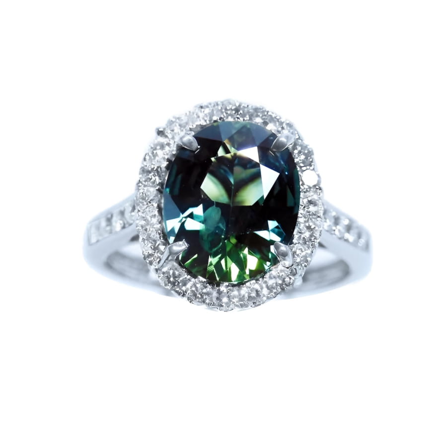 Australian sapphire ring for women oval cut with a sparkling bluish green hue, in a halo diamond crafted in 18K white gold. 