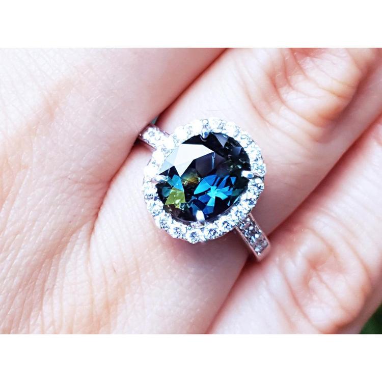 Australian sapphire ring for women halo diamond 18K white gold, on a person's finger