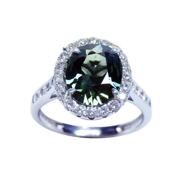 Oval bluish-green Australian sapphire ring with diamond halo and band in 18K white gold.