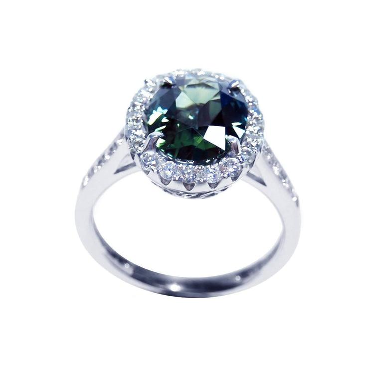 Oval bluish-green Australian sapphire ring with diamond halo, set in 18K white gold.