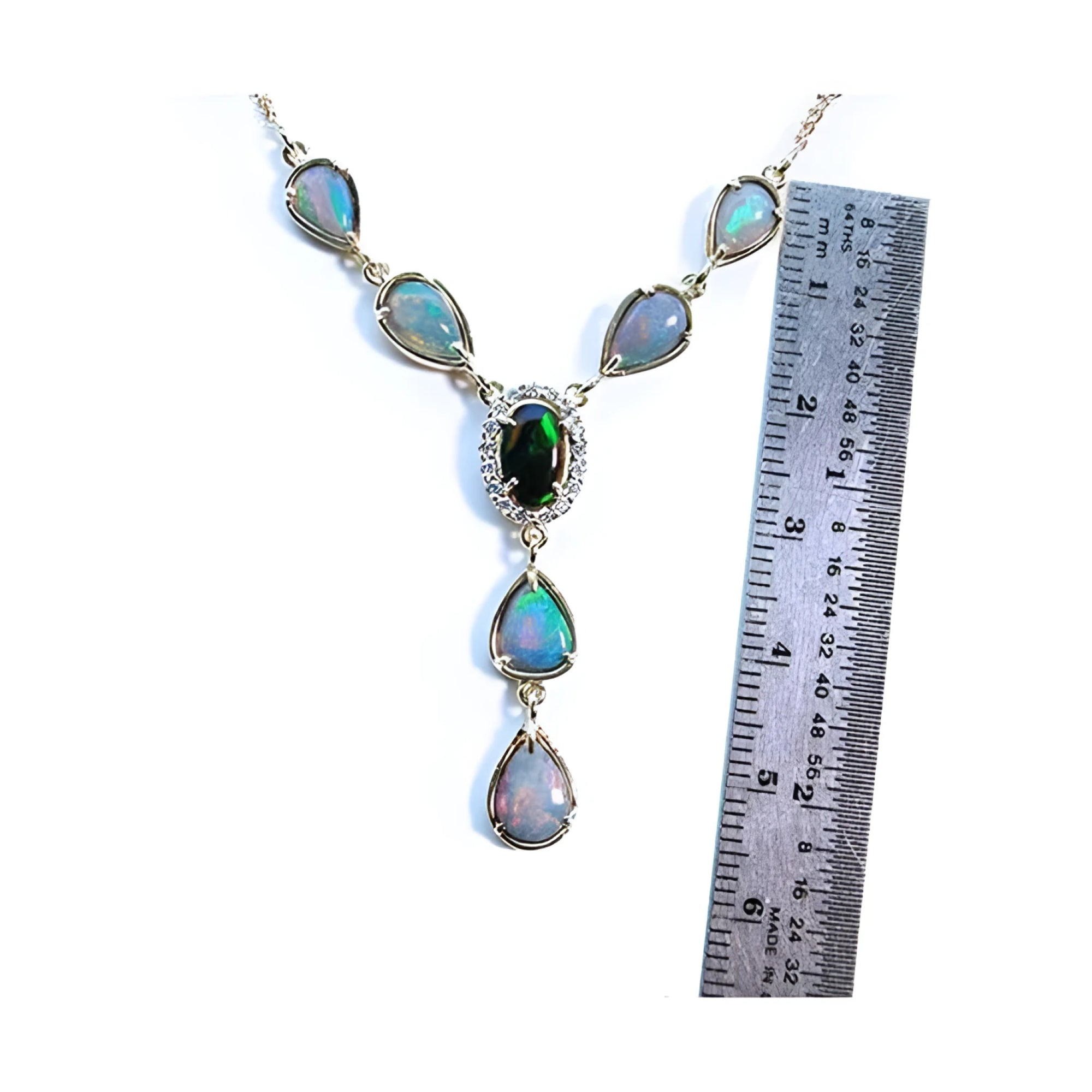14k yellow gold Australian black opal necklace with diamond halo and teardrop opals, shown next to a ruler.