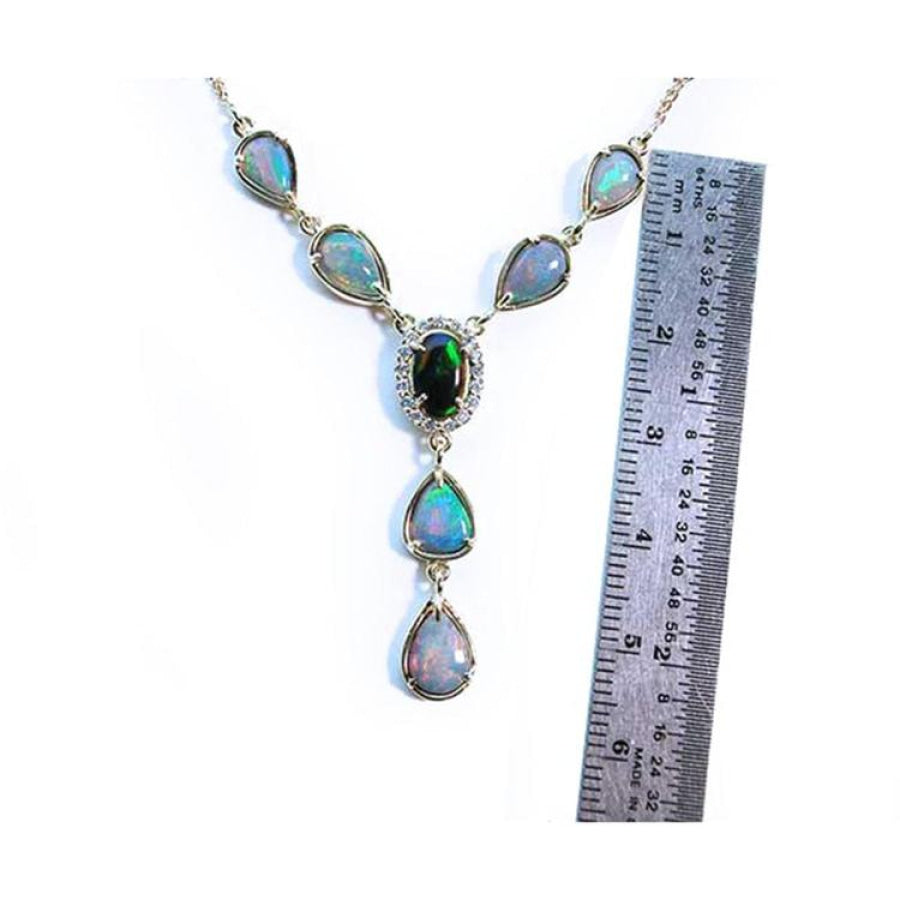 14k yellow gold Australian black opal necklace with diamond halo and teardrop opals, shown next to a ruler.
