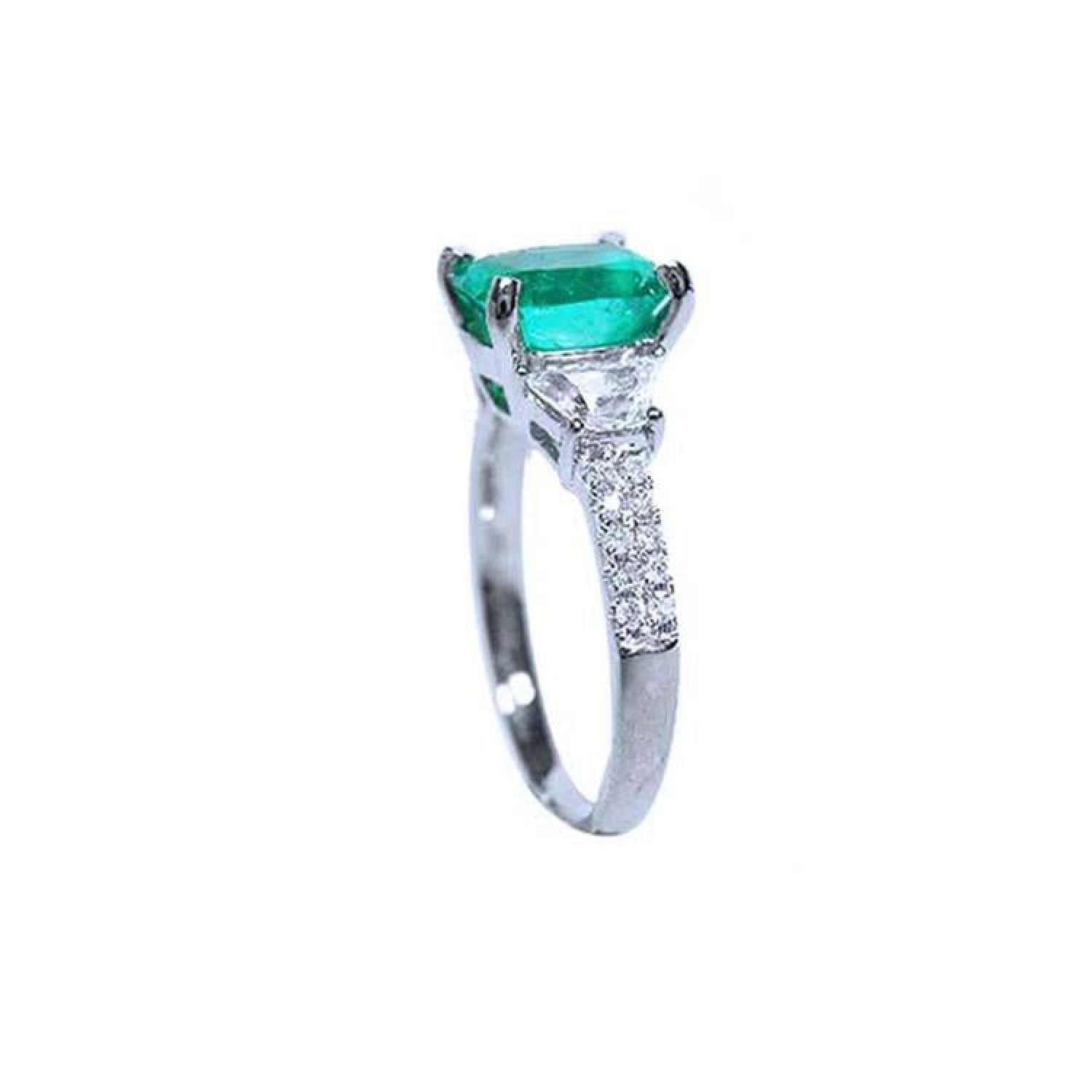 18K white gold ring with a cushion cut emerald and trapezoid side diamonds.
