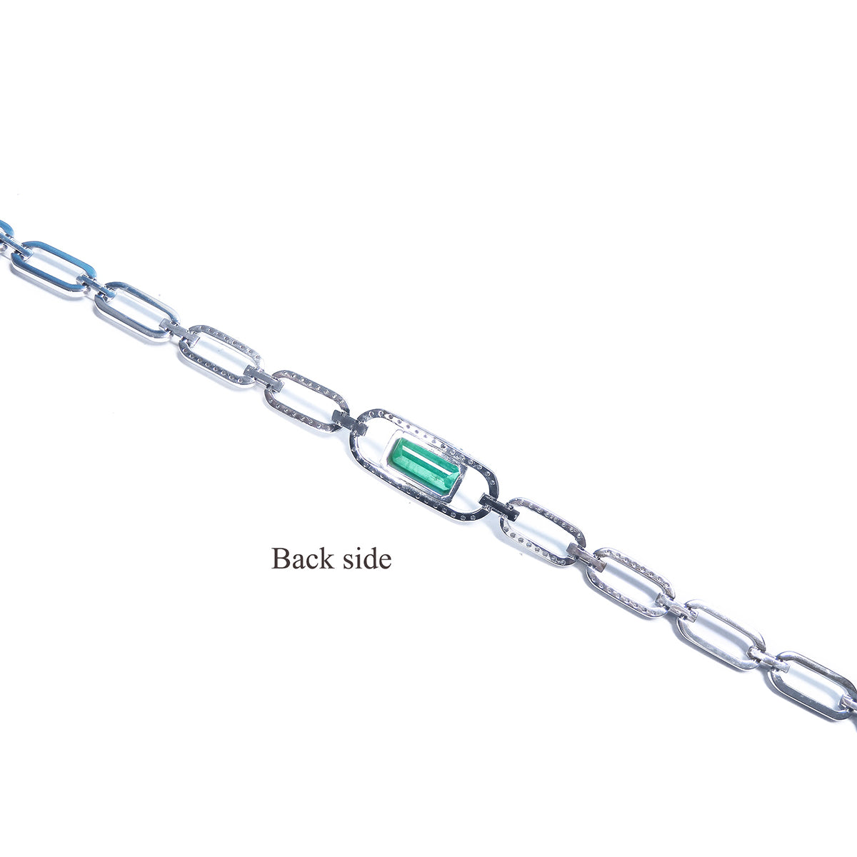 Backside view of a paperclip bracelet with a real emerald on a white background.