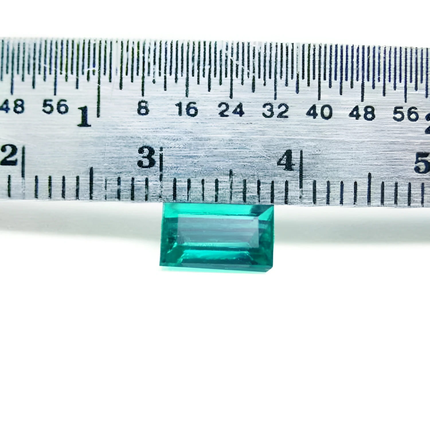 1.16 carat baguette cut loose Colombian emerald from Muzo mine, vivid bluish-green, shown with a ruler.