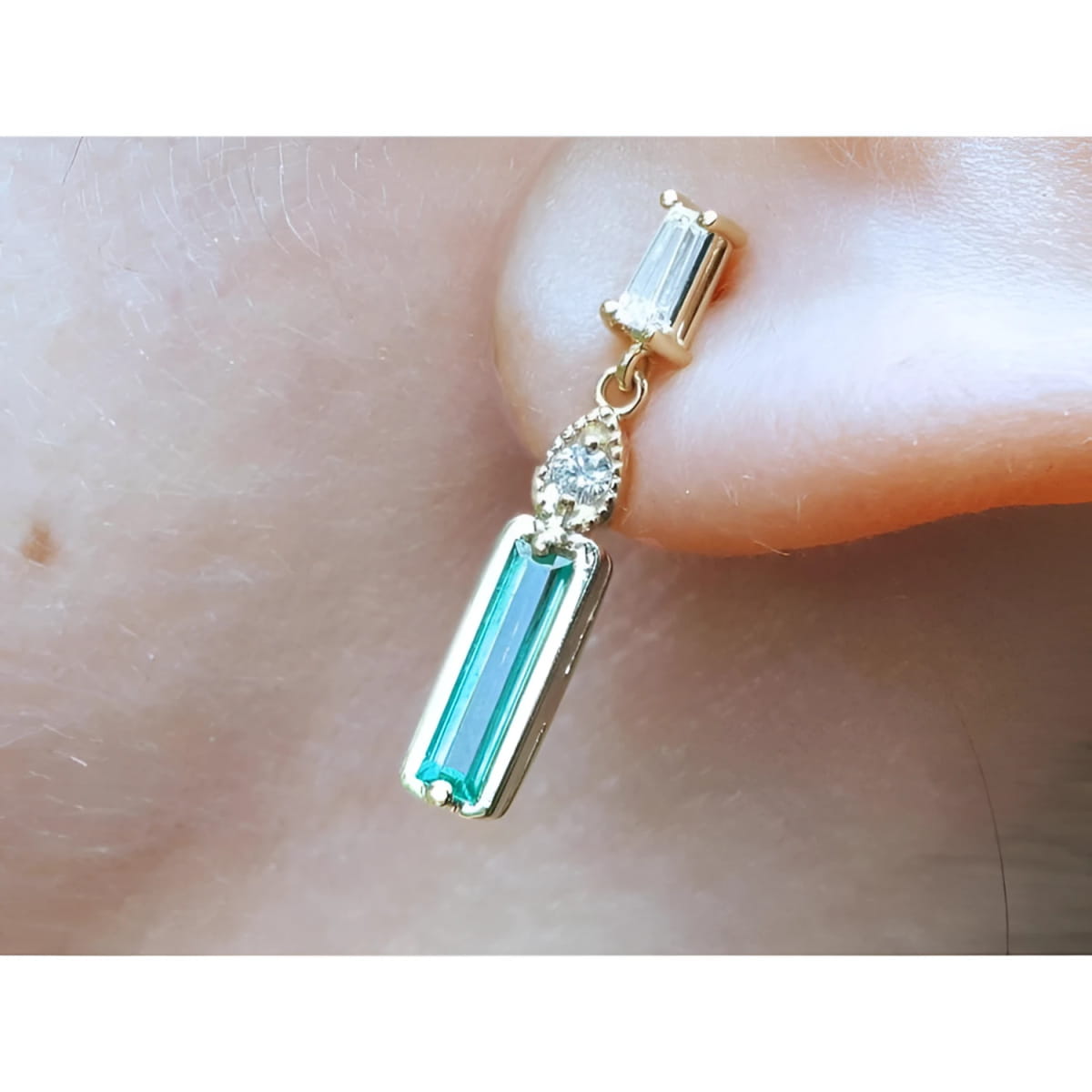 Dangle baguette cut natural emerald stud earrings on a person's ear