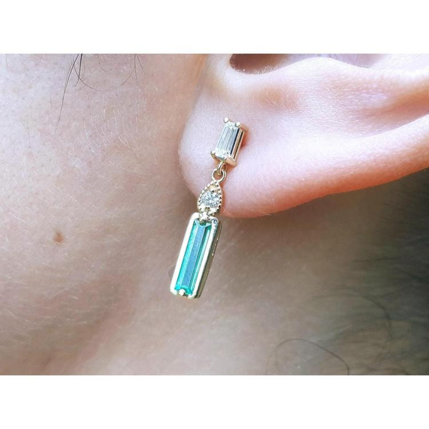 14K gold stud earring with baguette emerald, pear-shaped diamond, and tapered baguette diamond.