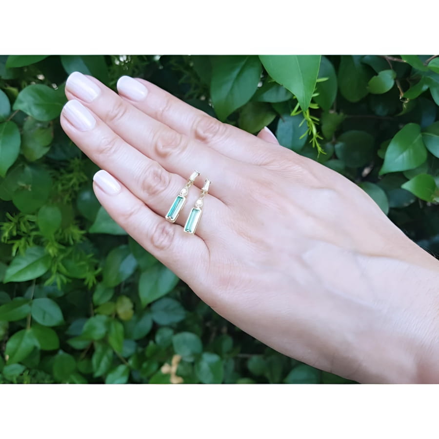 14K gold stud earrings with baguette-cut Colombian emeralds, pear-shaped extensions, and tapered baguette diamonds.