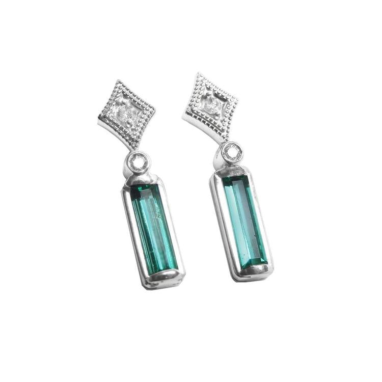 Pair of baguette cut emerald earrings with diamond accents made of 14k white gold. 