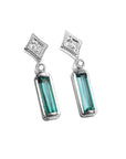Pair of baguette cut emerald earrings with diamond accents made of 14k white gold. 