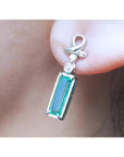 Natural baguette cut emerald earring with a top ribbon-like worn by a person
