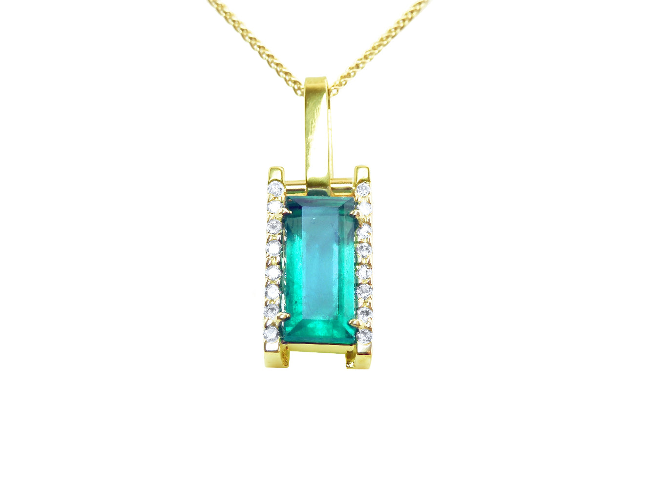 Gold pendant with a emerald baguette cut on a front position topside view.