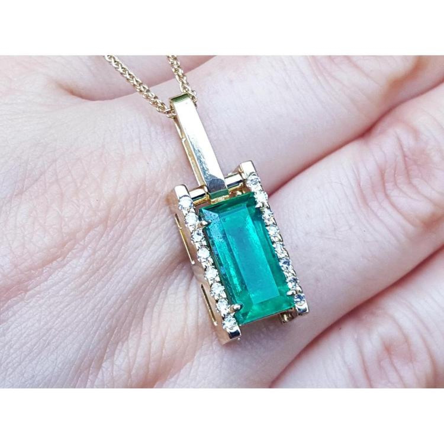 5.15 ct. baguette cut Colombian emerald pendant in 18K yellow gold with diamond accents.